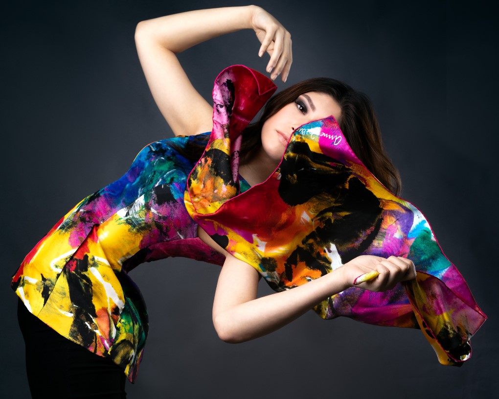 Fashion model in printed designer silk top holds wind-blown scarf