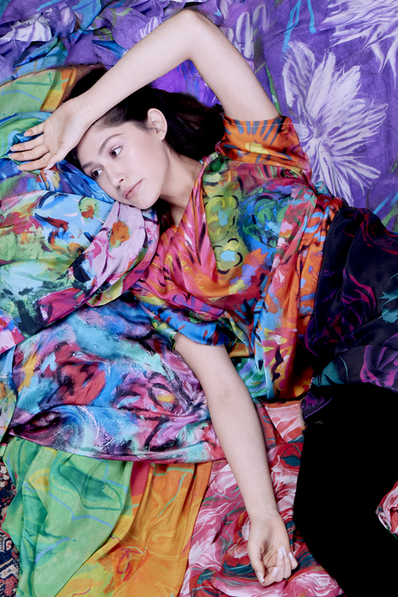 Lookbook photo of model surrounded by printed silks by designer Anne-Joelle Designs