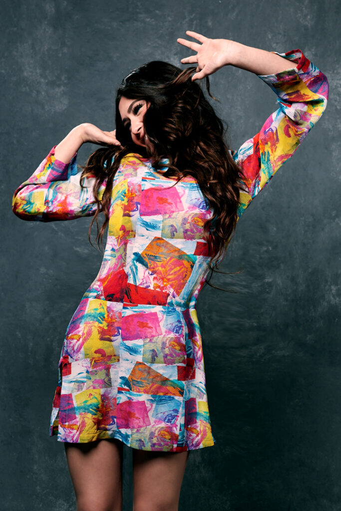 Happy model in colorful designer silk print dress for fashion lookbook.