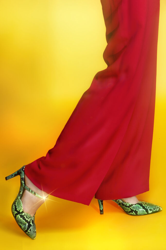 Fashion photography for Italian shoe designer, featuring green reptile pumps and bright red slacks on a yellow background.