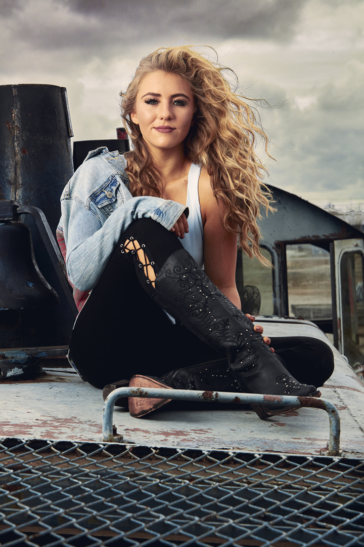 Personal branding image of female fashion stylist and model, seated on top of an abandoned train engine, storm clouds in the background.