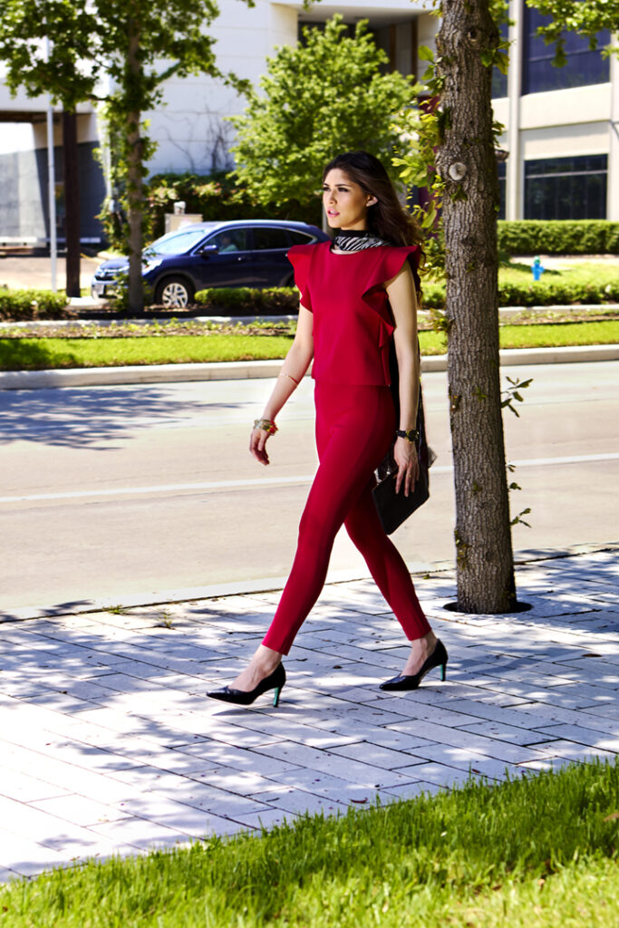 Young woman rests walks along busy urban street in stylish red pants and top separates. Grace on the Go collection of Work in Process Style. Gerard Harrison, Houston fashion photographer.